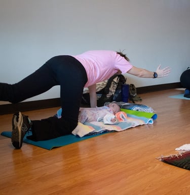 Mother in Spinal Balance yoga pose with Infant under her.