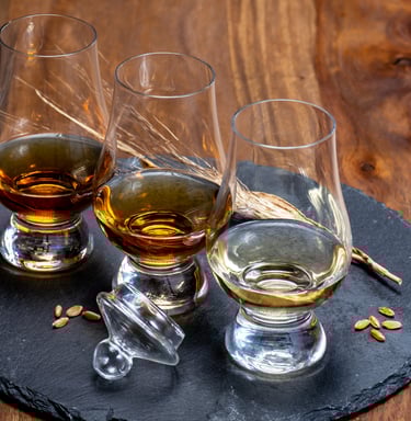 a table with glasses of whisky on a black slate with barley grains
