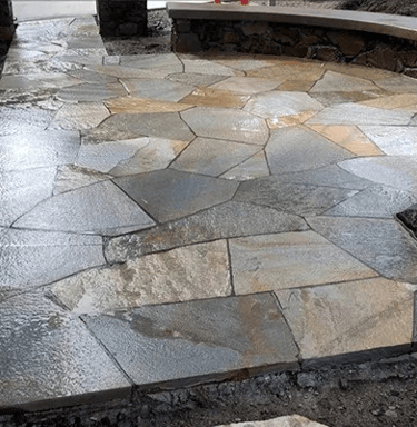 a stone patio with a bench and a fire hydrant