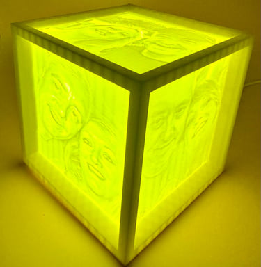 Custom 3D printed lithophane photo lamp cube with yellow LED light showing glowing family portraits.