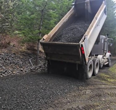 dump truck spreading gravel on driveway