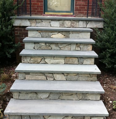 Custom bluestone front steps with natural fieldstone risers leading to a brick house entrance.