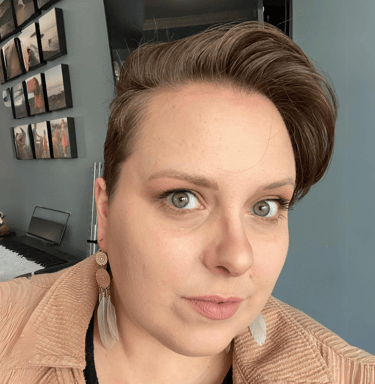 Head and shoulders of Wendy, a white woman with short brown hair, in front of a blue wall