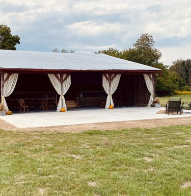 a barn with a covered patio decorated for fall with pumpkins