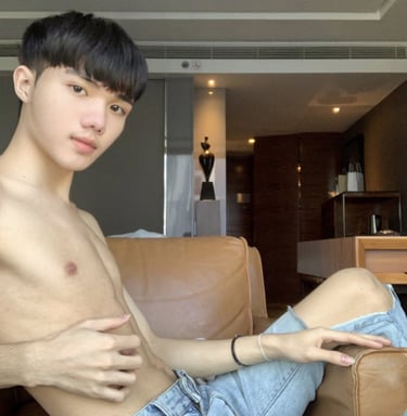 guy without a top wearing jeans sat on a sofa