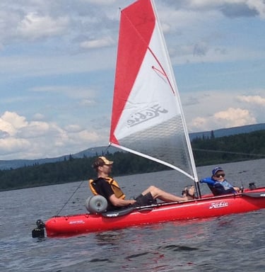 a man and a woman are sitting in a kayak with a sail