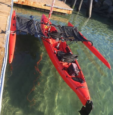 a red kayak is sitting on the water hooked to a platoon