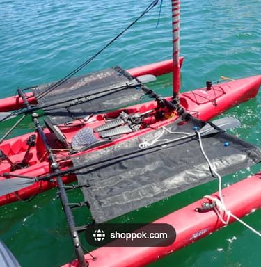 a red kayak with two outriggers with black trampolines