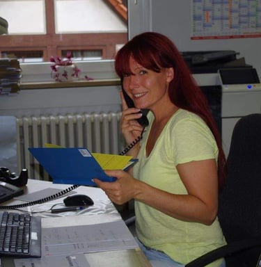 aFrau sitzt an einem Schreibtisch mit einem Telefon in der Hand