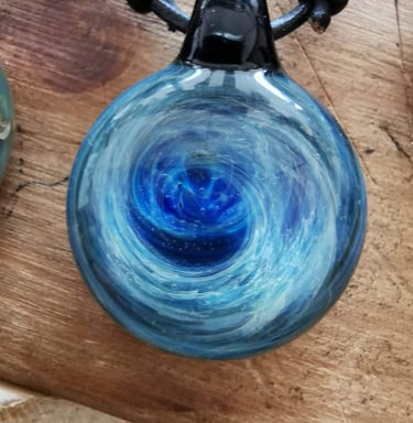 a blue glass pendant necklace with a swirl design
