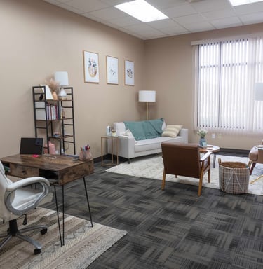 an office room with a couch, chair, and a table