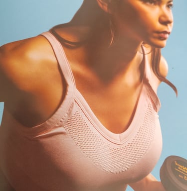 Athletic woman lifting a dumbbell in a pink sports bra for fitness strength training.