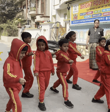 Preschool children in red tracksuits practicing a march outside Bright Foster Kids school in India.