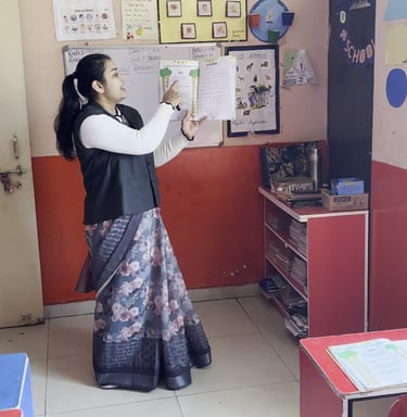 A teacher in a classroom holding up a textbook to teach elementary students.