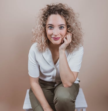 a woman sitting on a chair with her hand on her chin
