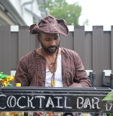 Professional bartender in a pirate costume serving drinks at an outdoor tropical cocktail bar.