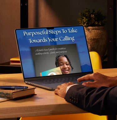 A laptop on a wooden desk displaying a faith-based guide for creatives seeking purpose and calling.