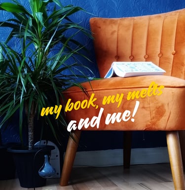 Cayla Henri: a chair with a book and a plant in front of a blue wall