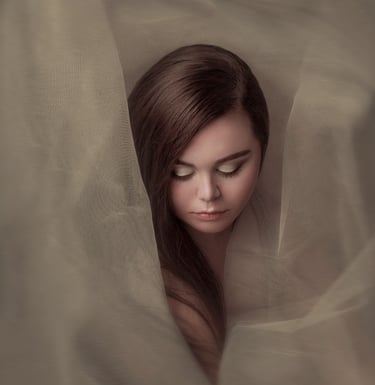 Creative portrait of a young woman wrapped in sheer tulle, creating an ethereal, dreamy effect.