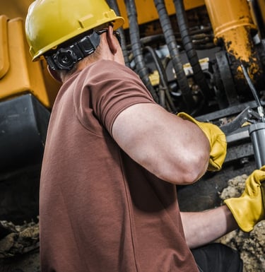 A man greasing his equipment using Grease Dispensers to properly Lubricate his machineries