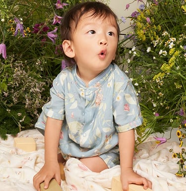 Bebê asiático veste macacão com estampa de arte original criada a mão da vida de um jardim