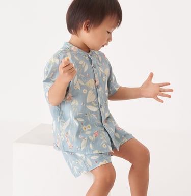 Menino asiático veste roupa com estampa de paisagem natural com animais e plantas