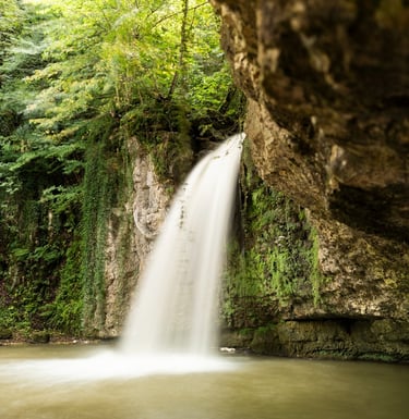 a waterfall in a cave in the woods