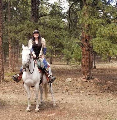a dog and two horses are riding on a trail