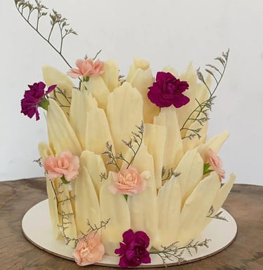 Bolo decorado com detalhes florais e texturas que imitam pétalas, ideal para festas e celebrações. D