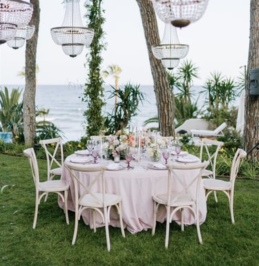 Elegant wedding table with pink linens, crystal chandeliers, and sea views at Villa El Rinconandles at Villa El Rincon