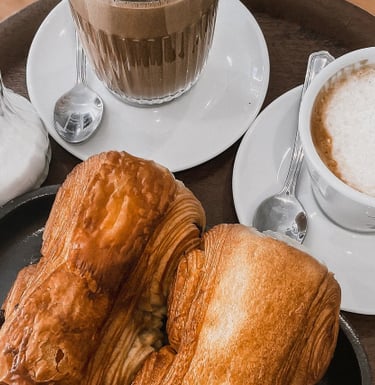 un plateau posé sur une table avec des cafés, chocolat chaud, et viennoiseries