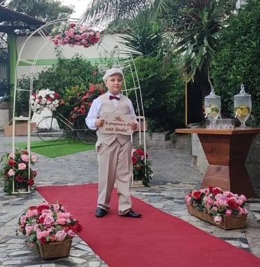 Garoto de nove anos, com um vestimenta classica de cor beje e camisa branca, e usando um boina beje.
