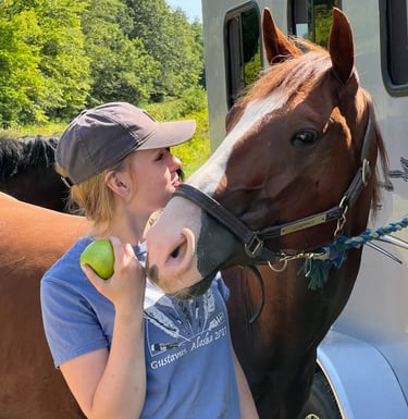 a woman in a hat and a horse at a trailer