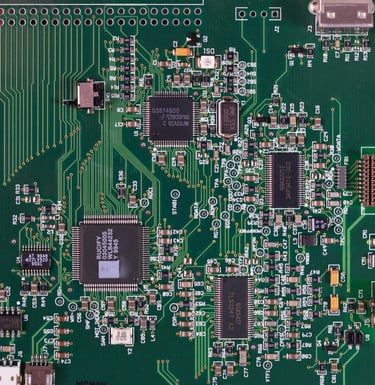 A forest green square computer motherboard with circuits, sockets, and processors on its surface.