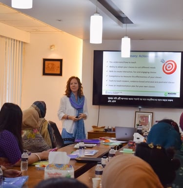 a woman in a white shirt is standing in front of a large screen talking to a room full of women