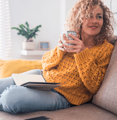 a woman sitting on a couch holding a coffee cup
