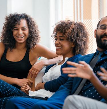 a group of people sitting on a couch laughing