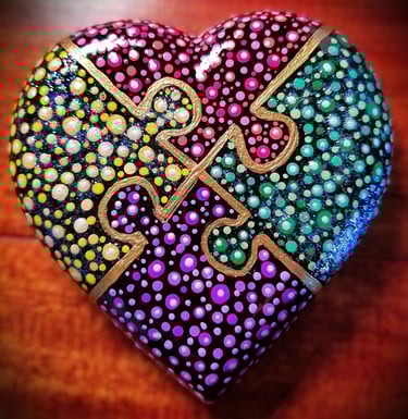 heart rock with 4 puzzle pieces in red, yellow , purple and green dots. 