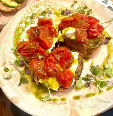 Sourdough tomato bruschetta with burrata cheese, pesto, and fresh microgreens on a plate.