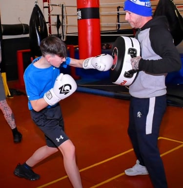 a man and a boy are boxing in a gym