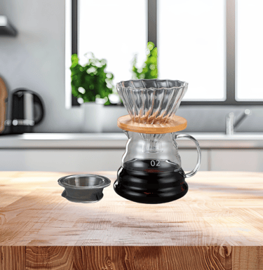 Cafeteira de vidro borossilicato com filtro e café preparado sobre bancada de madeira.