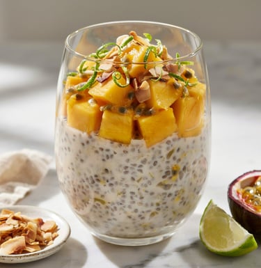 Tropical coconut chia pudding topped with fresh mango chunks, passion fruit, and lime zest in a glass.