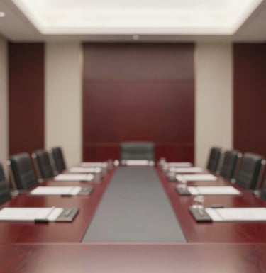 An interior shot of a high-end, contemporary boardroom with ivory walls and deep burgundy wood accents. A sense of quiet power and institutional credibility.