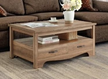 Rustic light oak wood coffee table with storage drawers and a lower shelf in a living room.