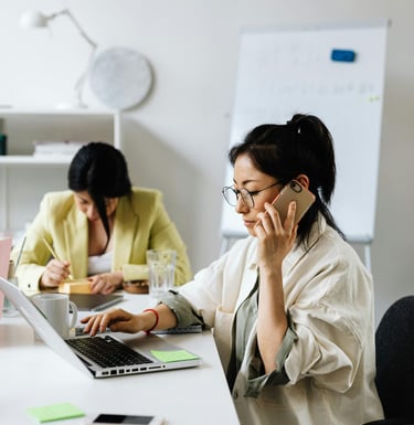 Support centre with two women answering phone call and replying to email.