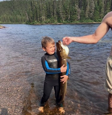 a child holding a fish on a lake