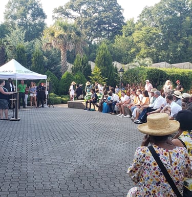 People gathered listening to speakers at the Atlanta Botanical Garden