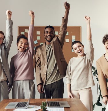 a group of people standing around a table with laptops