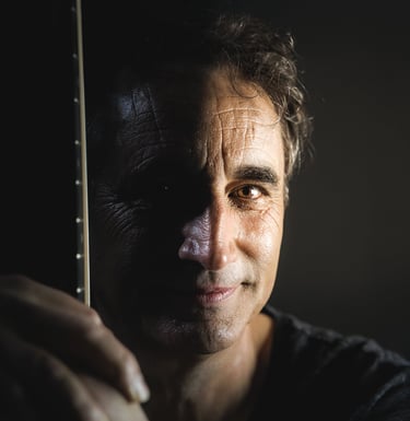 Photo de Joël Royer de face tenant sa guitare avec le manche de l'instrument devant lui