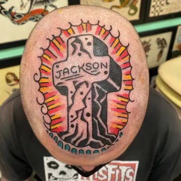 a man with a tattoo on his head of a cross with the name Jackson on it